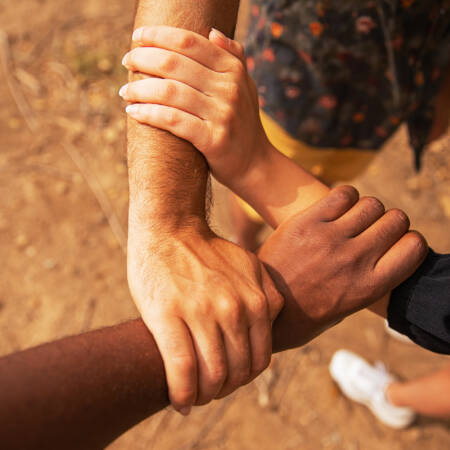 Kolmen eri etnisen ryhmän kädet toisiinsa tarttuneina.
